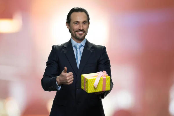 Felice uomo d'affari che mostra scatola regalo e pollice in su. — Foto Stock