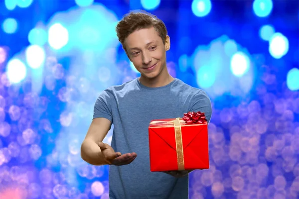 Lächelnder Junge streckt Geschenkbox in die Kamera. — Stockfoto