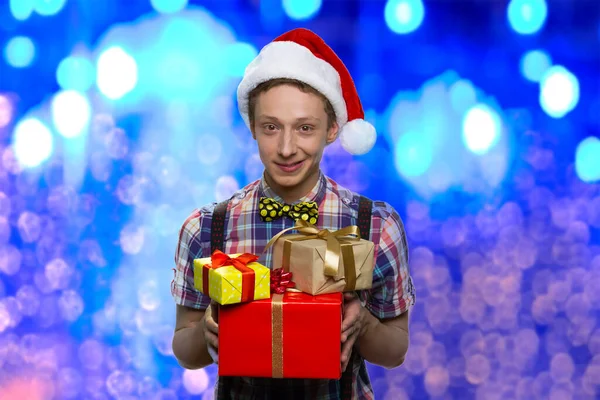 Menino de chapéu de Natal dando caixas de presente. — Fotografia de Stock