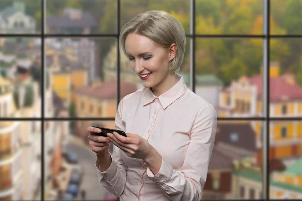 Smiling business woman using app on her smartphone.