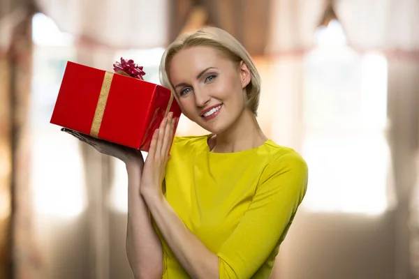 Mujer feliz sosteniendo caja de regalo sobre fondo borroso abstracto. — Foto de Stock