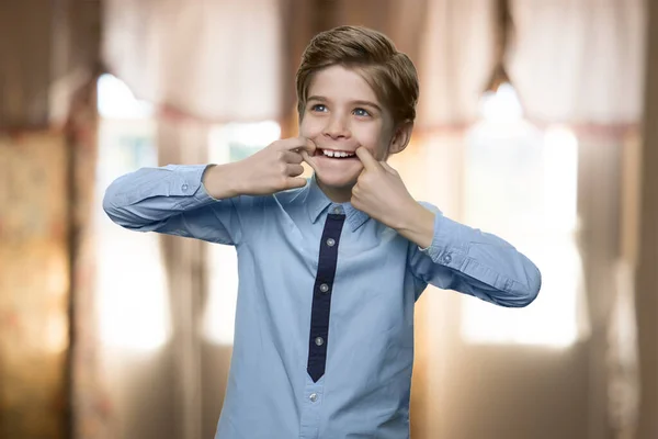 Niño haciendo divertido tirando de la cara con los dedos en la boca. —  Fotos de Stock