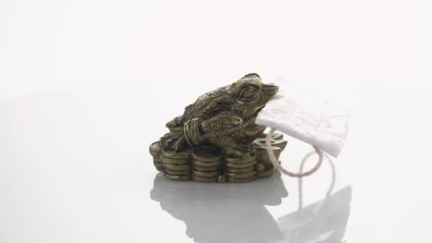 Feng Shui Frosch sitzt auf Geld mit medizinischer Maske im Mund. — Stockvideo