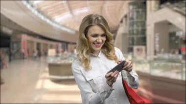 Heyecanlı genç kadın akıllı telefondan oyun oynuyor..