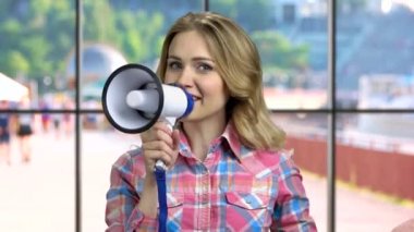 Genç, neşeli bir kadın megafona doğru konuşuyor..