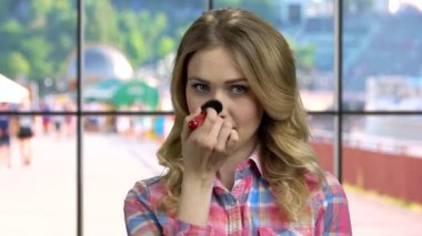 Pudra fırçası kullanan neşeli beyaz kız.