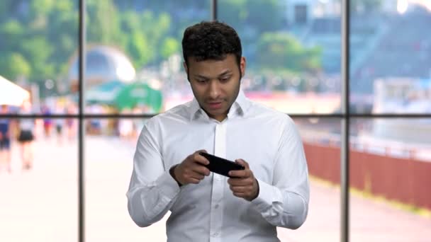 Emotionele zakenman speelt spel op smartphone. — Stockvideo