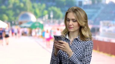 Dışarıdaki telefonunda uygulama kullanan genç bir kadın..