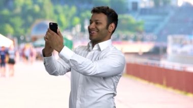 Genç yakışıklı adam akıllı telefonuyla selfie çekiyor..