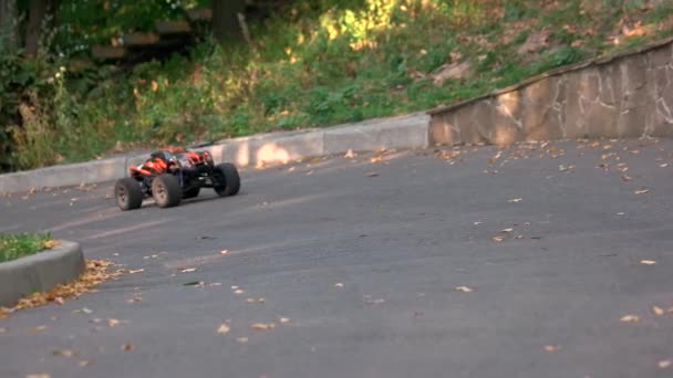 RC monstro caminhão passeios na estrada e explode folhas. — Vídeo de Stock