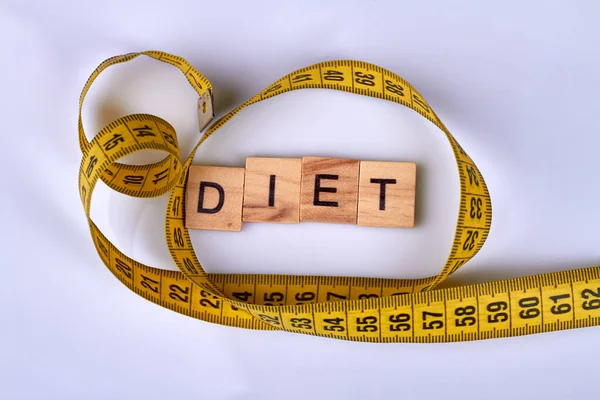 Diet word and measure tape on white surface.