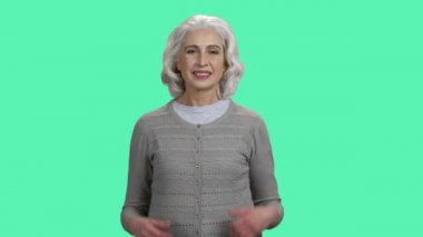 Gülümseyen olgun bir kadın iki parmağını kaldırıyor..