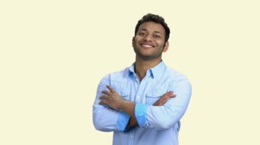 Genç gülümseyen adam beyaz arka planda kollarını kavuşturdu.