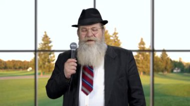 Kendinden emin kıdemli işadamı mikrofona konuşuyor..