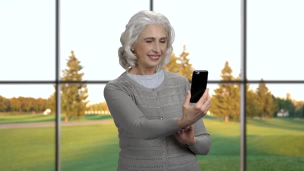 Mosolygós érett nő fényképezés az ő smartphone. — Stock videók