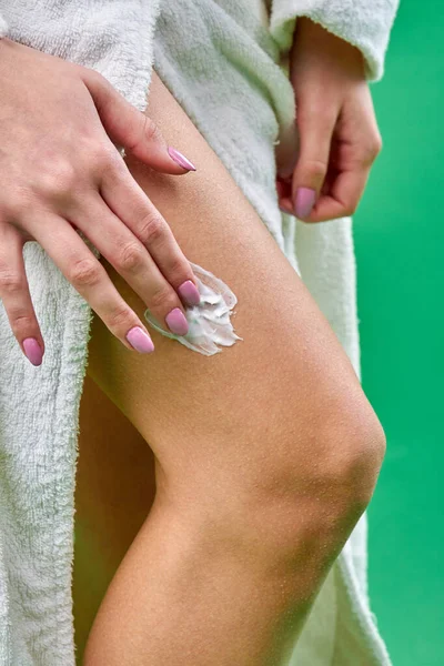 Женщина намазывает крем на ногу. — стоковое фото