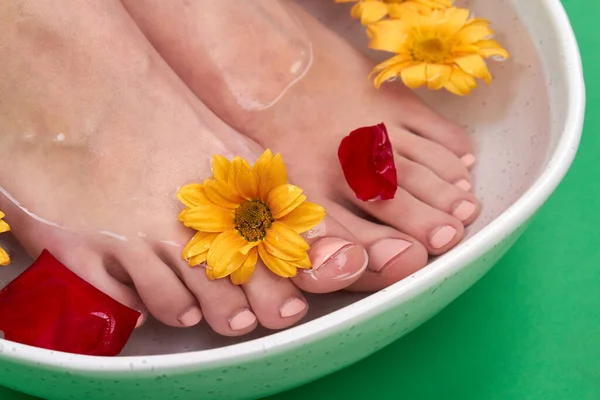 Close-up female feet with flowers in a bowl. — Stock Photo, Image