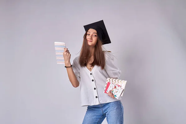 Beautiful graduate girl is holding the copybooks.