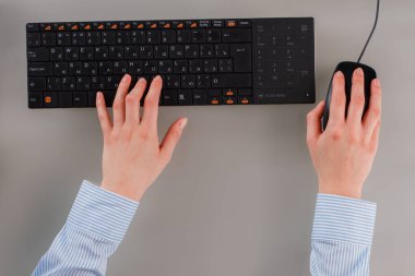 Bilgisayar klavyesi ve fare kullanan kadın eller.