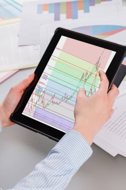 Tablet bilgisayarını çizelgelerle tutan kadın eller.