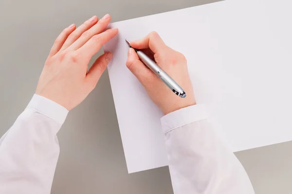 Mão feminina segurando caneta e escrevendo em papel em branco. — Fotografia de Stock