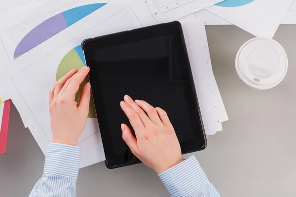 Workspace with female hands, digital tablet, documents and coffee cup.