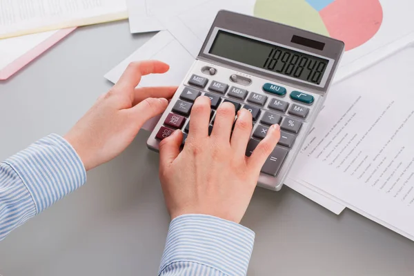 Mani femminili utilizzando la calcolatrice mentre si lavora con i documenti. — Foto Stock