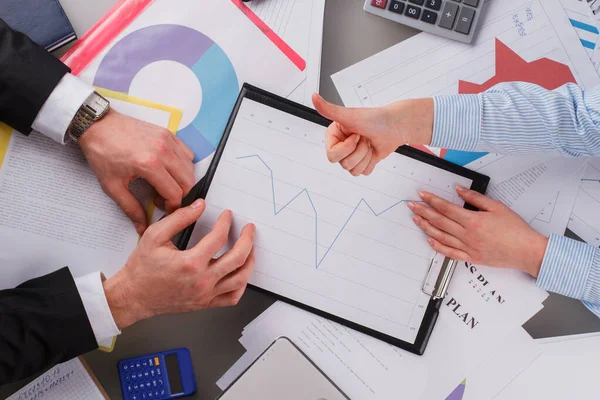 Zakelijke vrouw tonen duim omhoog over tafel met financiële kaarten. — Stockfoto