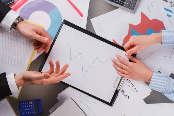 Zakenman en -vrouw bespreken financiële grafieken. — Stockfoto