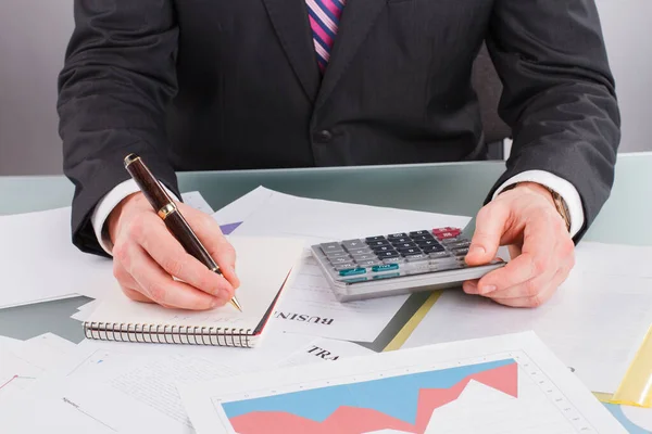 Affärsman eller revisor gör en anteckning när du använder miniräknare. — Stockfoto