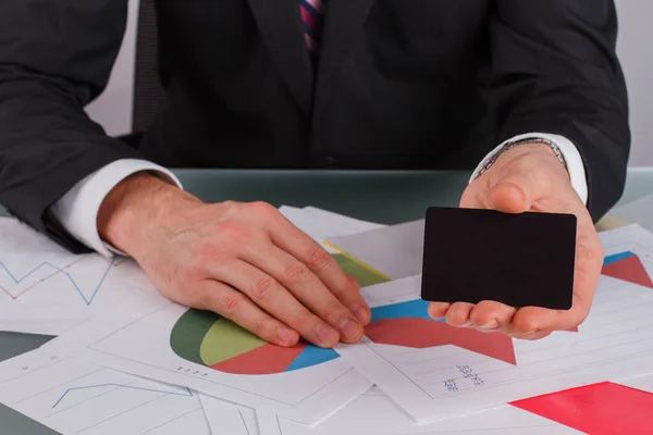 Üzletember vagy pénztáros névjegykártyát ad az asztalnál ülve. — Stock Fotó