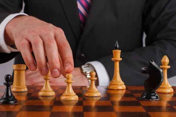 Empresario mano sosteniendo una pieza de ajedrez en un tablero de ajedrez. — Foto de Stock