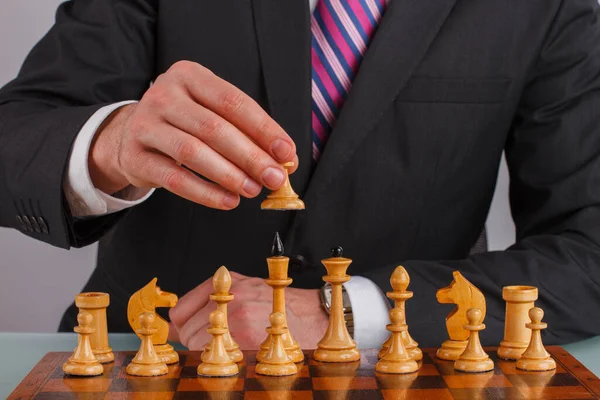 Empresario mano sosteniendo una pieza de ajedrez sobre tablero de ajedrez. — Foto de Stock