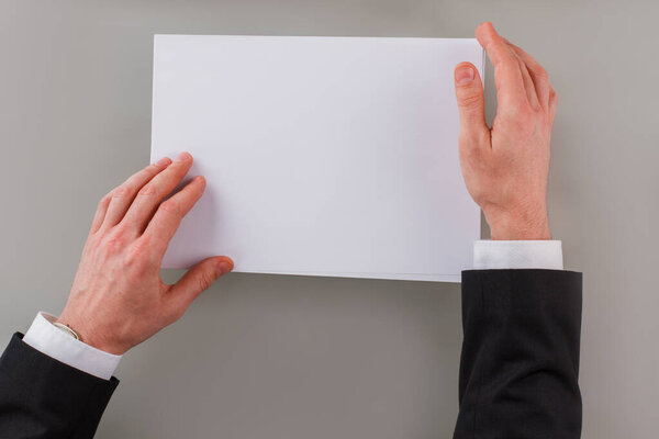 Businessman hands holding blank paper sheet.