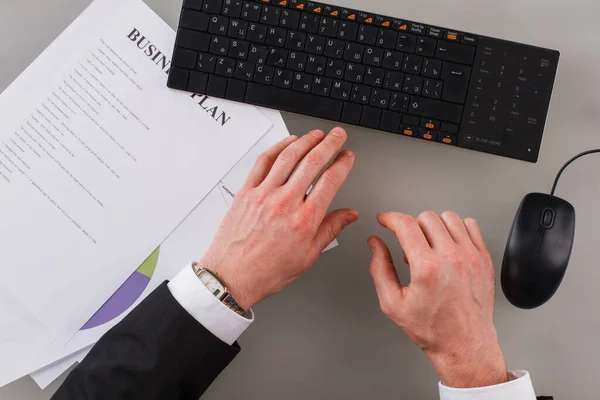 Widok na ręce biznesmena pracującego z klawiaturą i dokumentami. — Zdjęcie stockowe