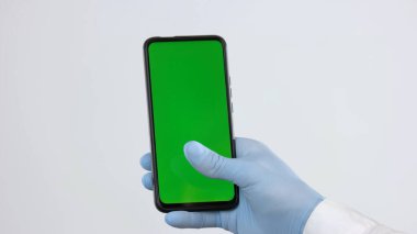 Koruyucu eldivenli el akıllı telefonu tutar.