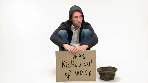 Ülő munkanélküli fickó kartonnal és adománykalapban.. — Stock Fotó