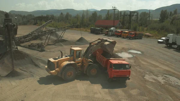 Gul grävmaskin häller kol i en lastbil. — Stockfoto
