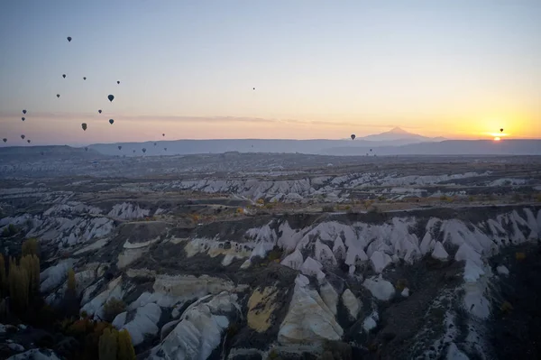 Paisaje rocoso con globos voladores al atardecer. — Foto de Stock