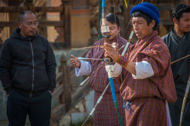 Erkekler okçulukta yarışıyor. Bhutan 'ın Ulusal Kıyafetleri.