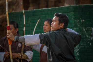 Erkekler okçulukta yarışıyor. Bhutan 'ın Ulusal Kıyafetleri.