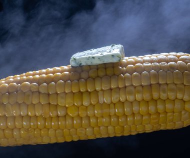 Siyah arka planda tereyağlı buharlı mısır..