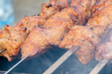 Metal bir şişte barbekü yapmak. Barbeküde ızgara et. Dilimlere kesilmiş taze et şişleri. Geleneksel doğu yemeği, barbekü. Kömür ve alev ızgarası