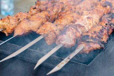 Metal bir şişte barbekü yapmak. Barbeküde ızgara et. Dilimlere kesilmiş taze et şişleri. Geleneksel doğu yemeği, barbekü. Kömür ve alev ızgarası