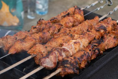 Metal bir şişte barbekü yapmak. Barbeküde ızgara et. Dilimlere kesilmiş taze et şişleri. Geleneksel doğu yemeği, barbekü. Kömür ve alev ızgarası