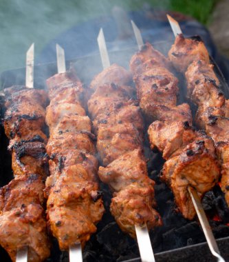 Metal bir şişte barbekü yapmak. Barbeküde ızgara et. Dilimlere kesilmiş taze et şişleri. Geleneksel doğu yemeği, barbekü. Kömür ve alev ızgarası
