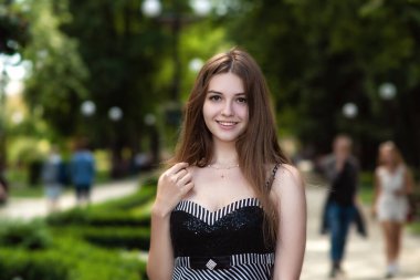 Mutlu gülümseyen kız şehir parkında yürürken yakın plan portresi