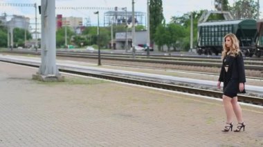 Kıvırcık saçlı sarışın tren beklerken eğleniyor.