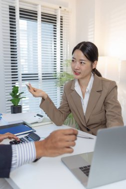 İki iş adamı modern bir ofiste finansal çizelge ve stratejileri tartışıyor. Resmi bir toplantıda fikir alışverişinde bulunur, raporları analiz eder ve çözümleri müzakere ederler..