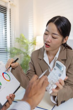 İş arkadaşları renkli çizelge ve raporları gözden geçirmek için finansal bir toplantıdalar. Etkili sonuçlar elde etmek için fikir alışverişinde bulunur, notlar alır ve stratejileri analiz ederler..